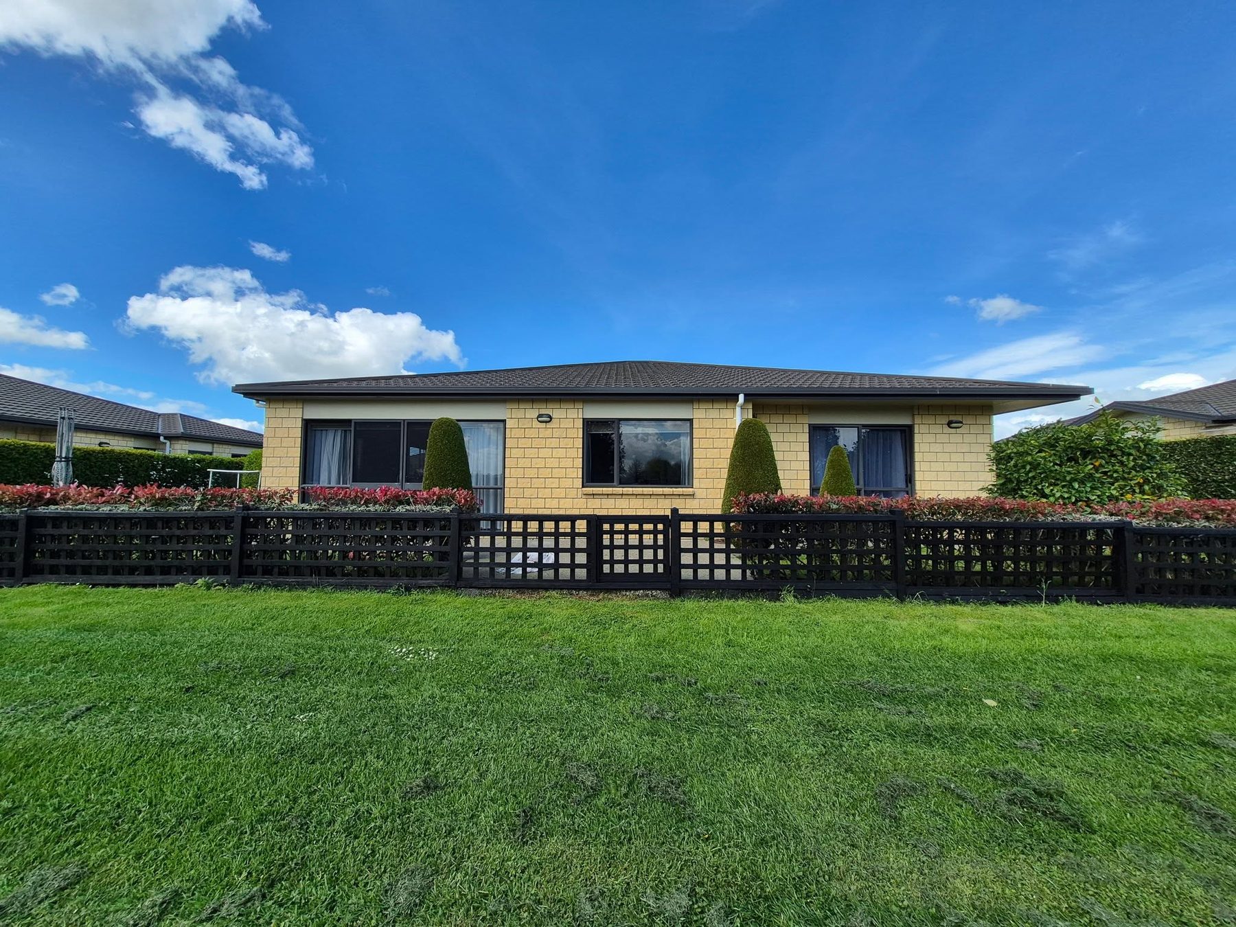 A home with a freshly painted exterior and black fencing